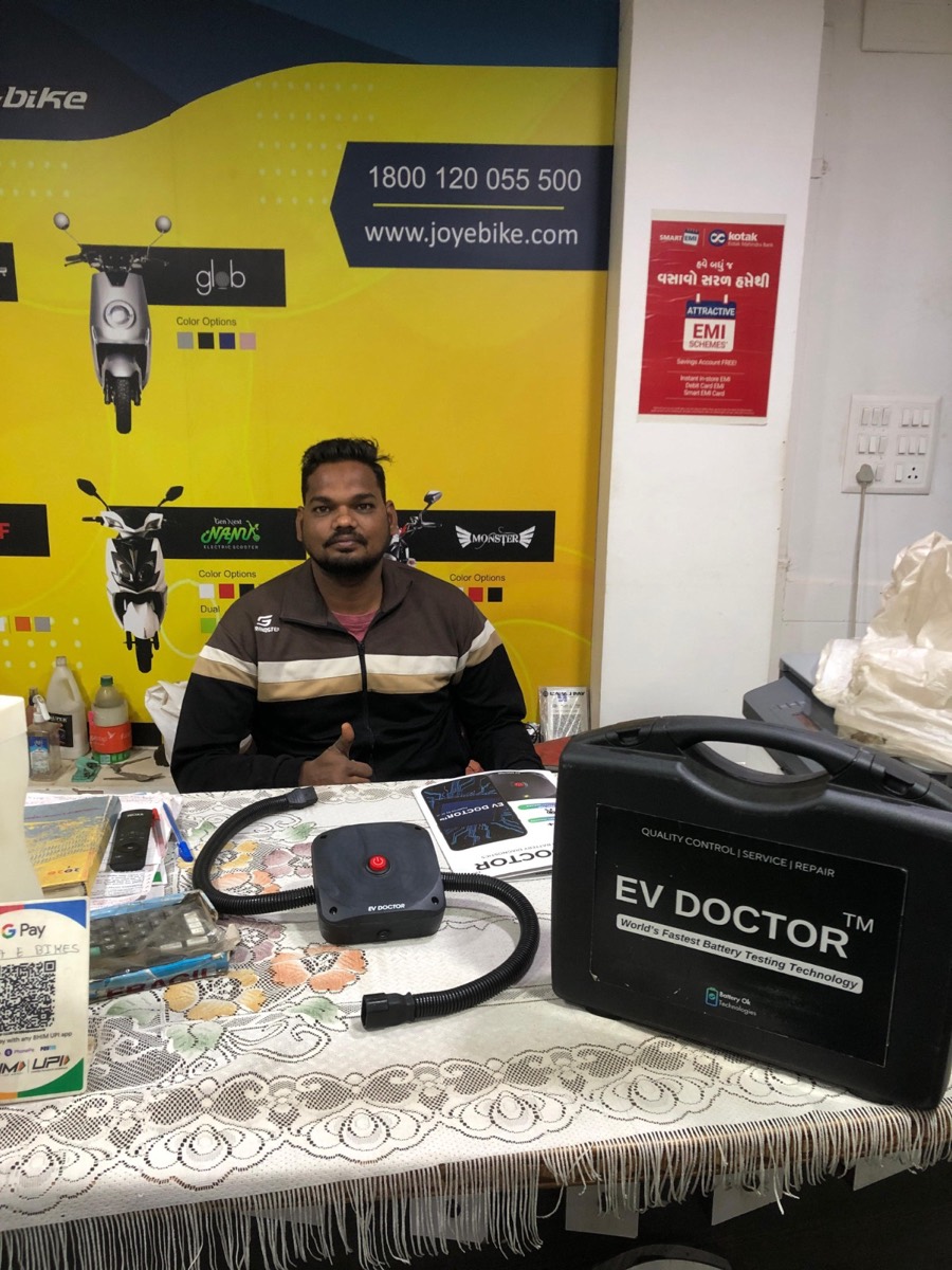 Electric vehicle professional using the EV DOCTOR battery testing kit at a dealership